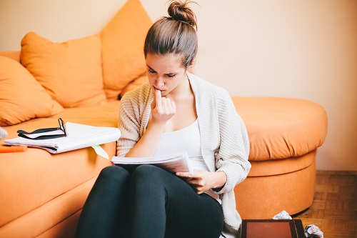 young woman biting nails while studying