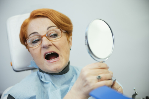 woman looks at teeth in mirror
